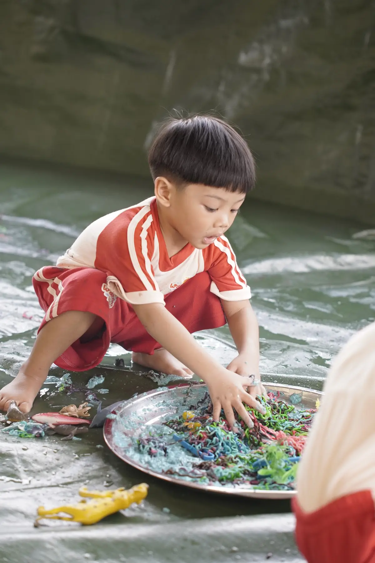 Anak bermain sensori dengan wadah berisi bahan bertekstur